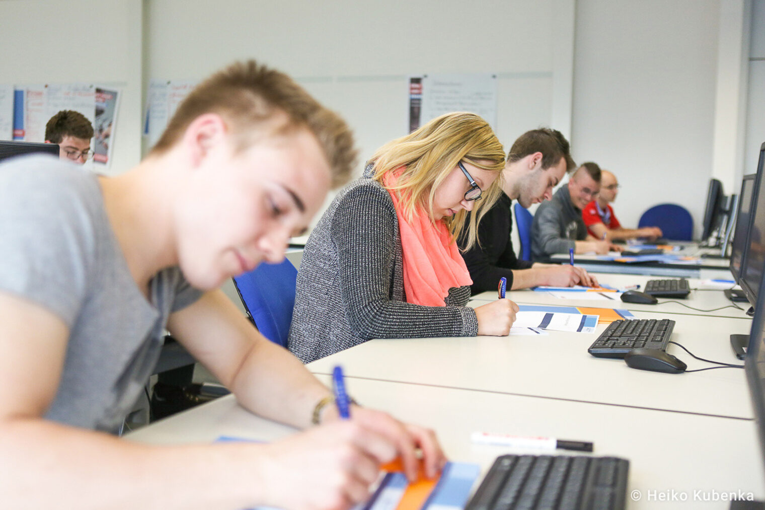 Teilnehmende eines Seminars schreiben auf Arbeitsplätter Auszubildende nehmen an einem Seminar teil und schreiben auf Arbeitsplätter, während sie vor Computern sitzen