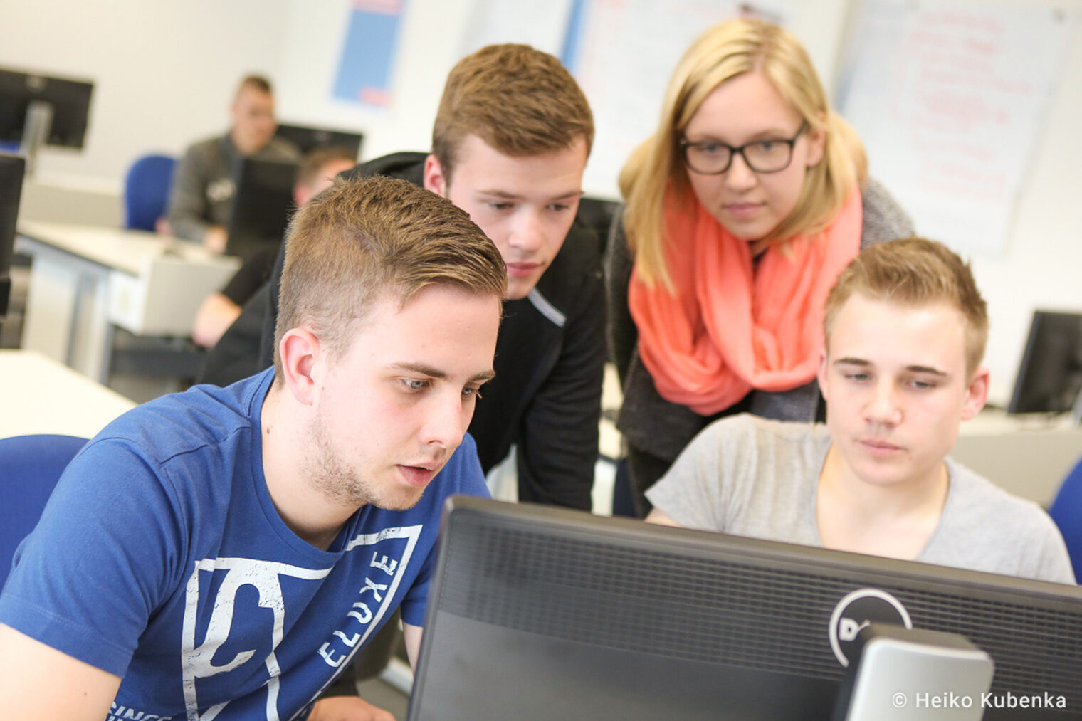 Seminarteilnehmende schauen auf einen Computermonitor Vier Auszubildende die an einem Kurs teilnehmen schauen auf ein Computerdisplay